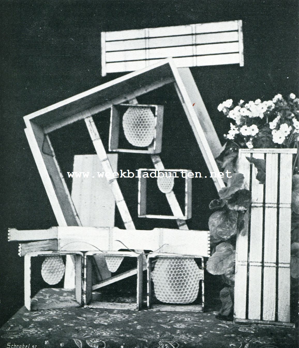 DEELEN VAN EEN SECTIEKASTJE. In 't midden het kastje zelf; erin hangen twee secties, die reeds door de dijen in bewerking genomen zijn, er bovenop staat een sectieafscheider of separator, evenals op den voorgrond rechts. Naast elkaar: drie secties, meer of minder bewerkt; daar bovenop: een uiteengevouwen sectie en twee klemveeren. Heel achteraan: het aansluitplankje