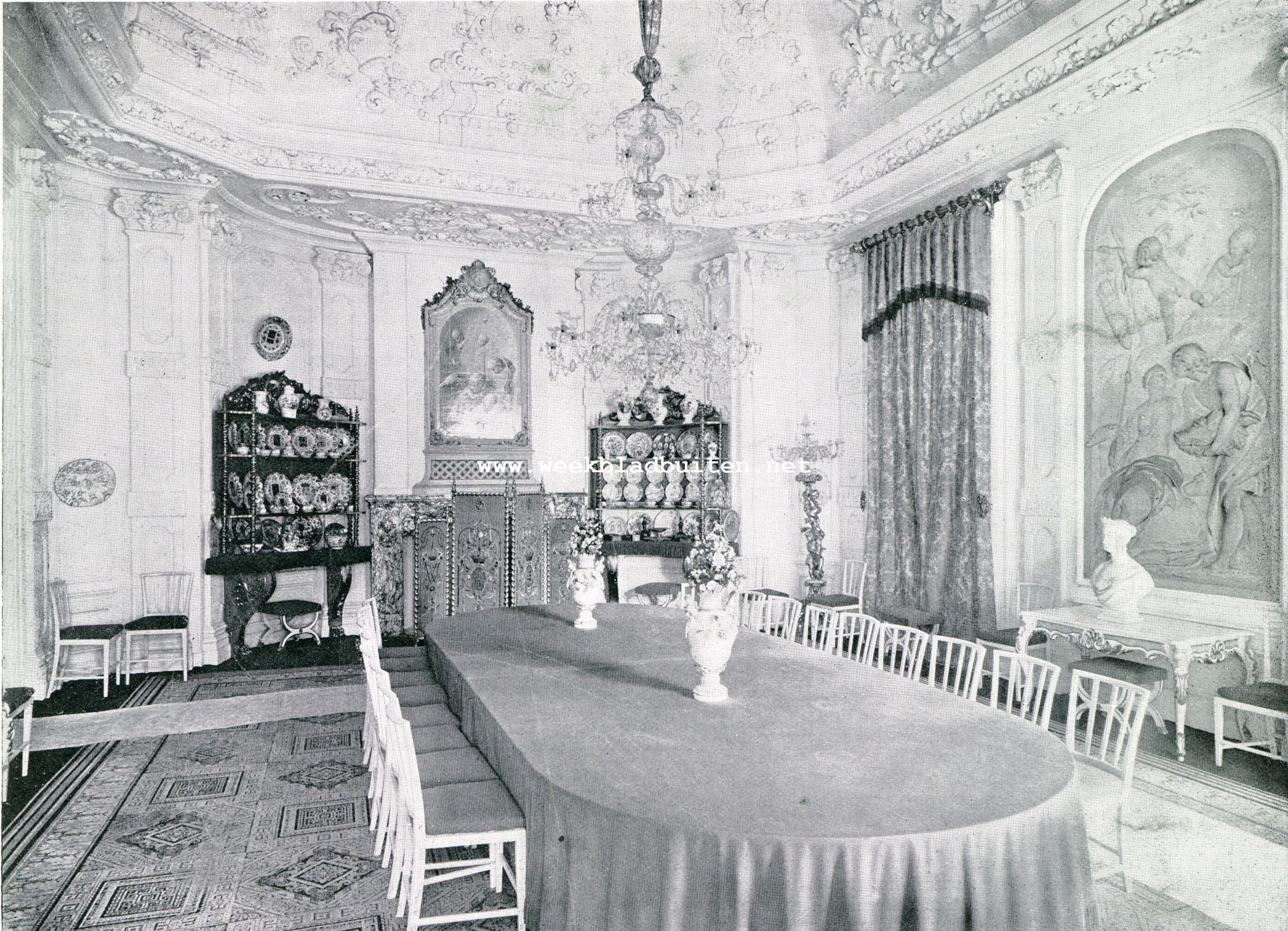 HUIS TEN BOSCH. DE WITTE ZAAL. Vroegere eetzaal, met rijk-versierd plafond en aan de wanden eenige zeer fraaie medaillons van De Witt. Ter weerszijden van de schoorsteen twee tagres met porceleinen borden en ander gerei