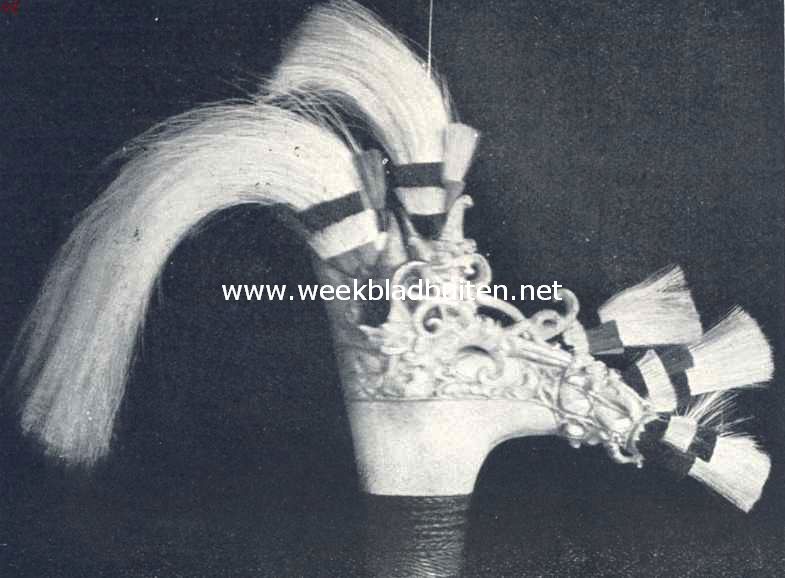 Handvat van een mandau (zie ook afb. hieronder). Het bestaat uit met magische figuren besneden hertshoorn en is met bundeltjes haar, rood, zwart en wit, versierd. De lange haren waren vroeger van menschen afkomstig. (In menschenhaar schuilt veel levenskracht.) Het onderste deel is omgeven met vlechtwerk van dun koperdraad